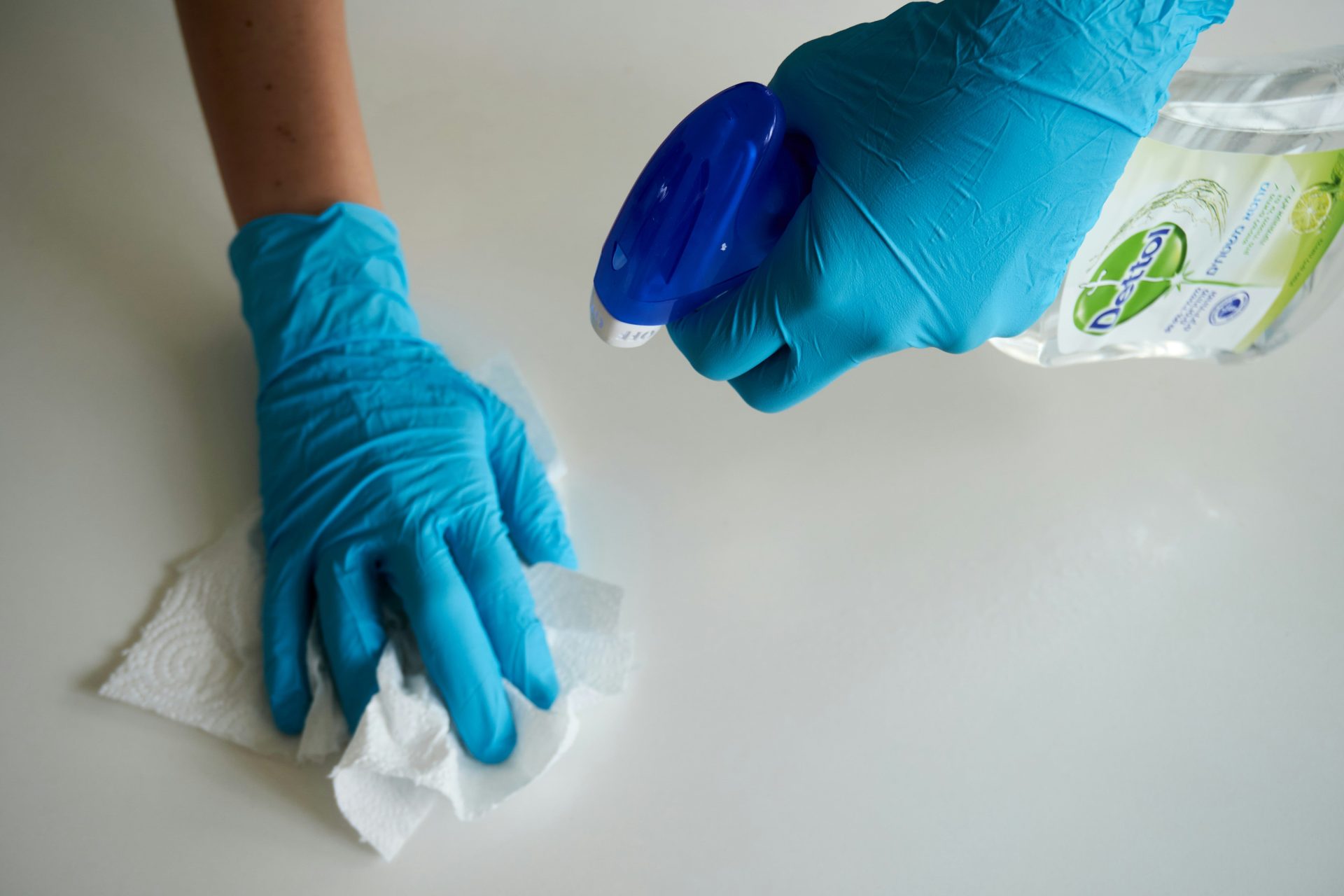 Person mit blauen Handschuhen hält ein weißes Textil